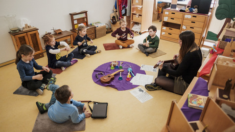 Mehrere Kinder mit einer Erzieherin und Musikinstrumenten