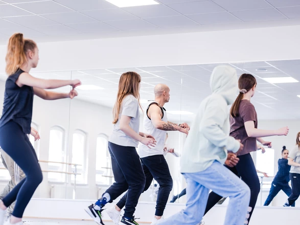 Gruppe übt Tanzschritte vor Spiegel