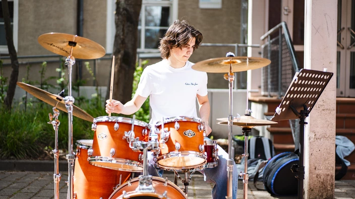 Jugendlicher spielt Schlagzeug auf dem CJD Campus Gelände